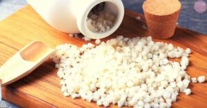 coarse granulated Epsom salt in a wooden scoop and container for chemical-free ice melting