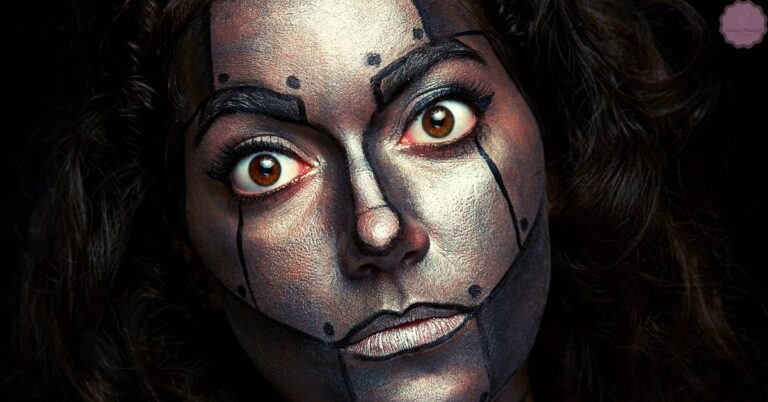 a person with dramatic face paint featuring bold, angular black lines resembling cat eye and winged eyeliner techniques to create an elongated eye effect
