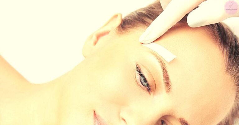 a person receiving a dermatological treatment on the forehead near eyebrow area with a handheld device, possibly for hair or skin stimulation.