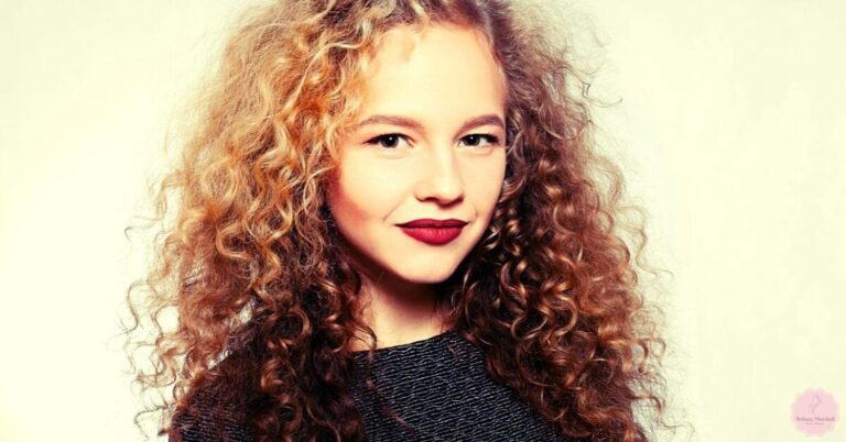 a woman with voluminous curly hair showcasing a classic perm style, wearing dark lipstick