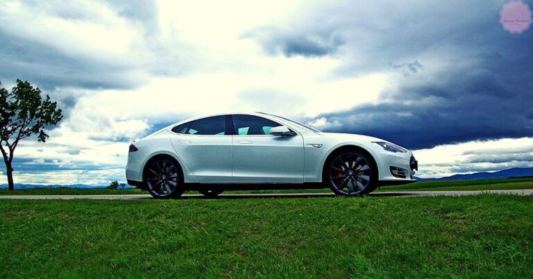 a sleek white Tesla electric car parked on a grassy field with dramatic storm clouds in the background
