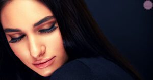 a person with closed eyes and long, well-maintained eyelash extensions resting gently on their cheek