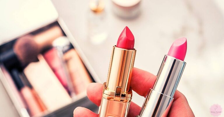 a hand holding two lipsticks with pink shades, one gold-toned and one silver-toned, against a blurred background of a makeup application guide.