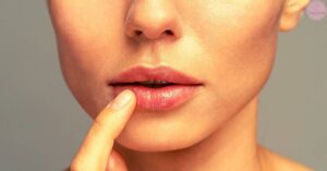 a person gently exfoliating their lips with a finger to remove dead skin.