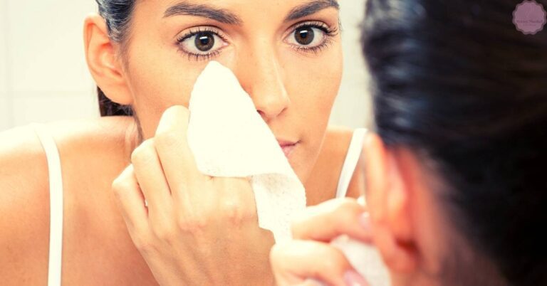 a person gently wiping their eye area with a damp washcloth to remove mascara