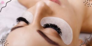 a person receiving eyelash extensions with adhesive patches applied to closed eyelids