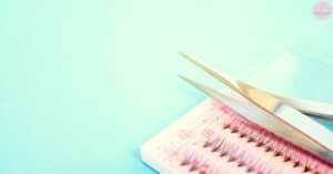 a pair of gold-tipped scissors trimming eyelash extensions on a decorative comb for lash extension correction