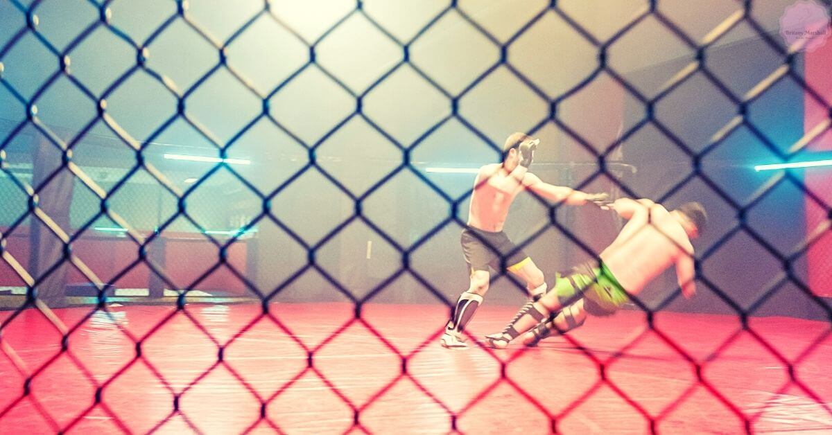 two mixed martial artists engaged in a grappling exchange inside a caged octagon.