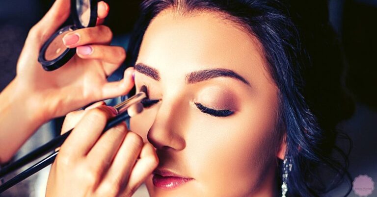 a person receiving precise eyeliner application with a makeup brush and mirror, showcasing detailed makeup technique.