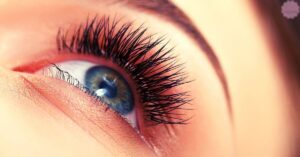 a close-up of a human eye with naturally wispy lashes and a soft, partially open eyelid.