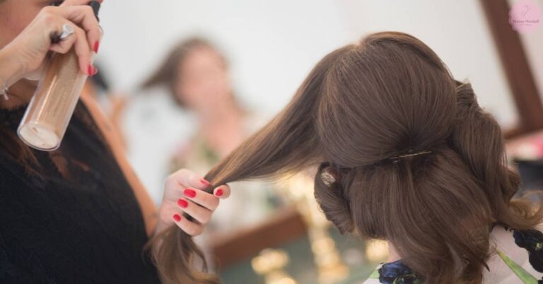 a hairstylist applying hairspray to secure an elegant updo on a bride’s hair for long-lasting hold