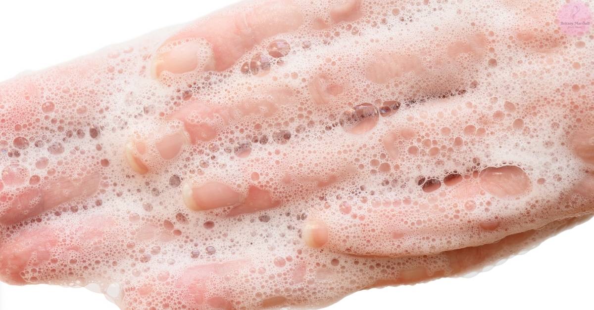 a close-up of foamy antibacterial body wash with natural ingredients like coconut oil, creating a bubbly texture for effective female body odor treatment.