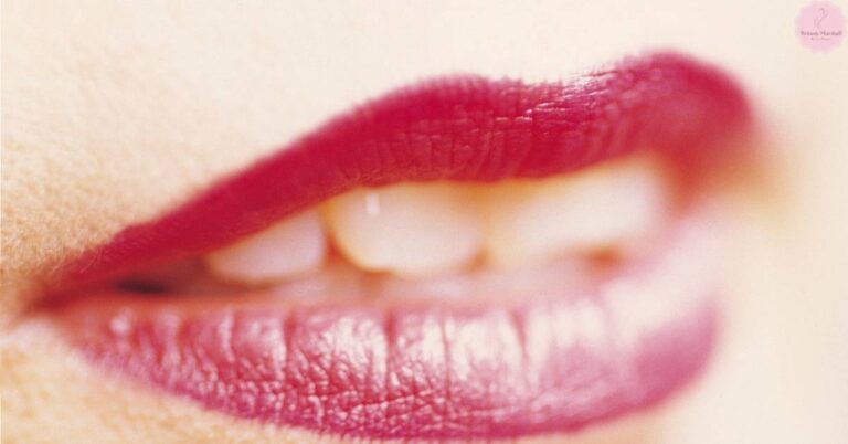 a close-up of lips with a bold, matte pink lipstick, showcasing a glossy lower lip detail.