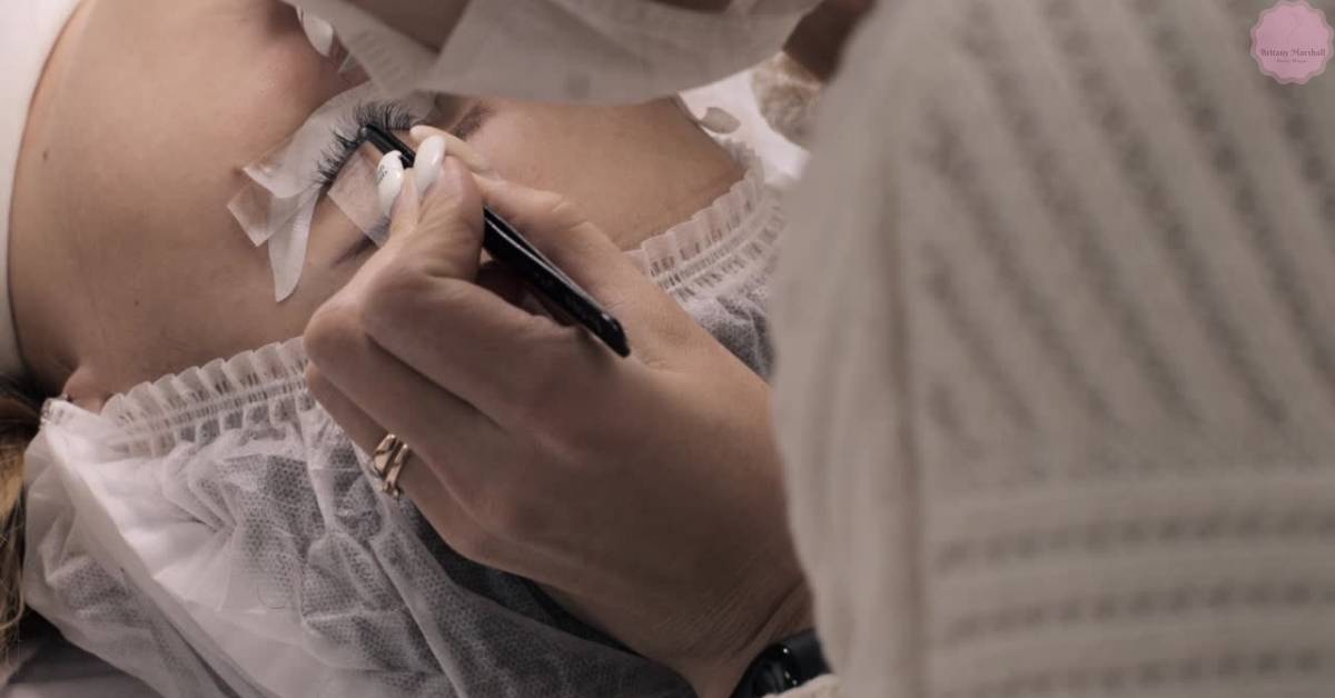 a person receiving eyelash extensions with tape applied to the lash line, showing potential irritation or dryness at the base.