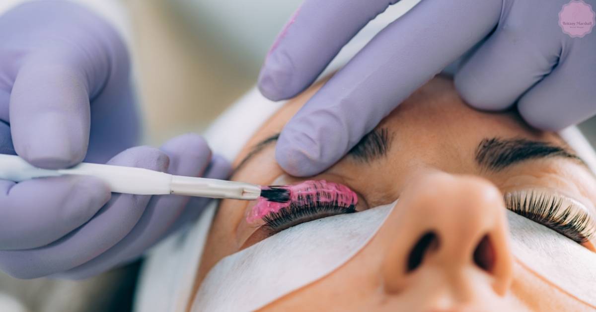 a professional trimming and shaping bent eyelashes with precision tools on a client’s closed eye.