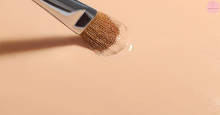 a makeup brush applying a sheer, light-coverage powder foundation on smooth skin.