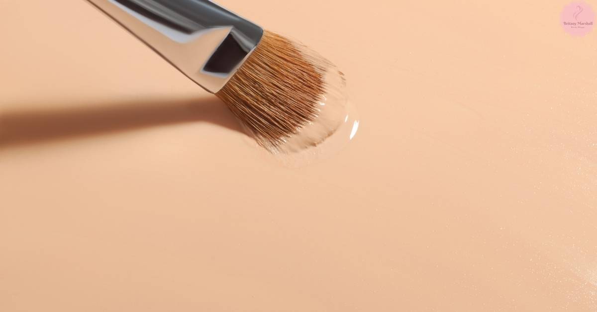 a makeup brush applying a sheer, light-coverage powder foundation on smooth skin.