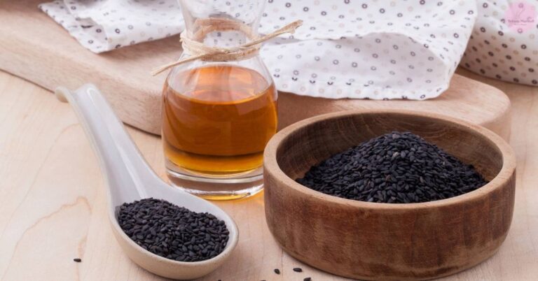 a wooden surface displaying black cumin seeds in a bowl and spoon, alongside a bottle of black seed oil, suggesting natural remedy uses