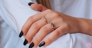 a person’s hands with black nail polish showcasing elegant black and silver ring-style nail art with subtle glitter accents.
