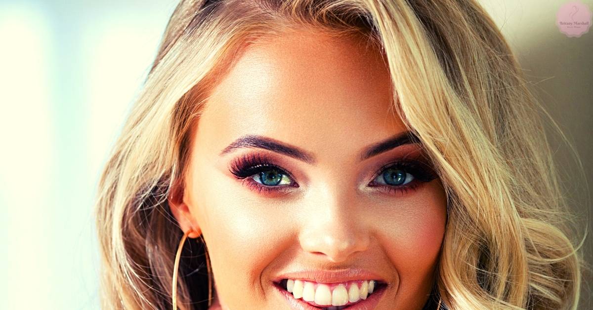 a smiling woman with blonde hair showcasing well-defined, voluminous eyelash extensions and natural makeup