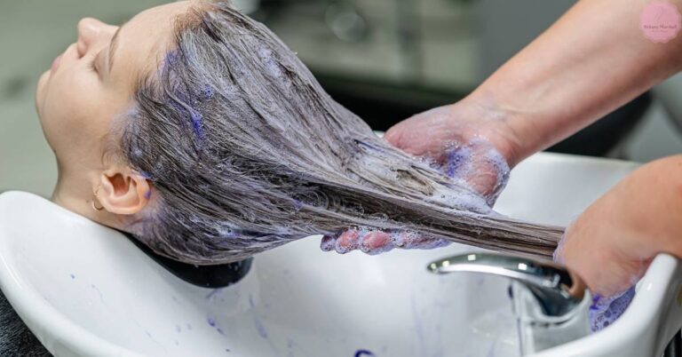 a person receiving a hair coloring treatment with developer applied to their hair at a salon sink.