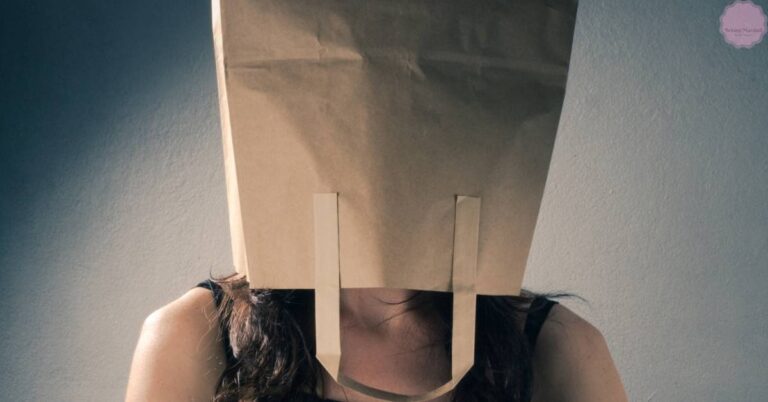 a person with their head covered by a paper bag secured with tape, obscuring their face.