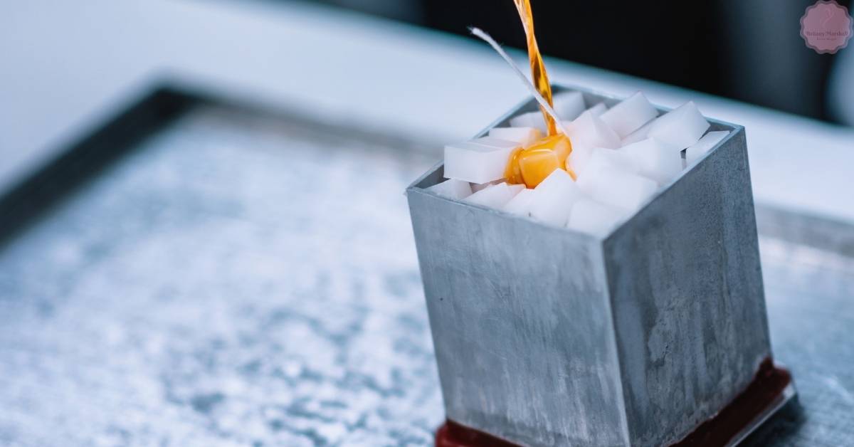 a close-up of a small metal candle mold with partially melted wax and an exposed wick, showing potential wax air bubbles forming during candle making.