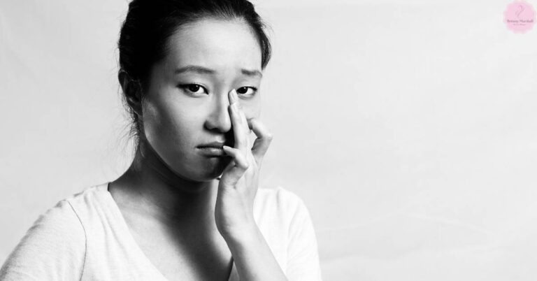 a person touching their nose and eye area, appearing thoughtful or concerned