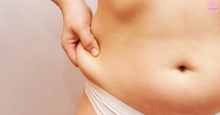 a hand applying pressure to the lower stomach area near the belly button, demonstrating a quick fix technique for a protruding tummy.