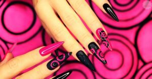 a pair of hands showcasing stylish acrylic nails with black and pink designs, highlighting nail art and durability.