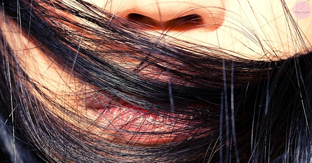 a close-up of hair tangled around a person’s mouth and throat area, illustrating how strands can lodge near the airway.