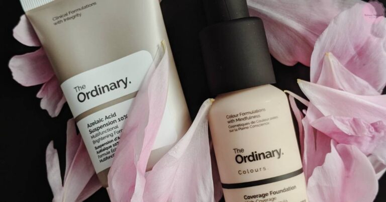 three The Ordinary skincare and makeup products: Azelaic Acid Suspension 10%, a tube of foundation, surrounded by pink peony petals.