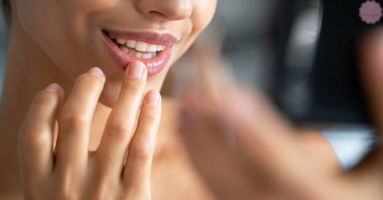 a person smiling while gently touching their lips, suggesting moisturized and protected lips.