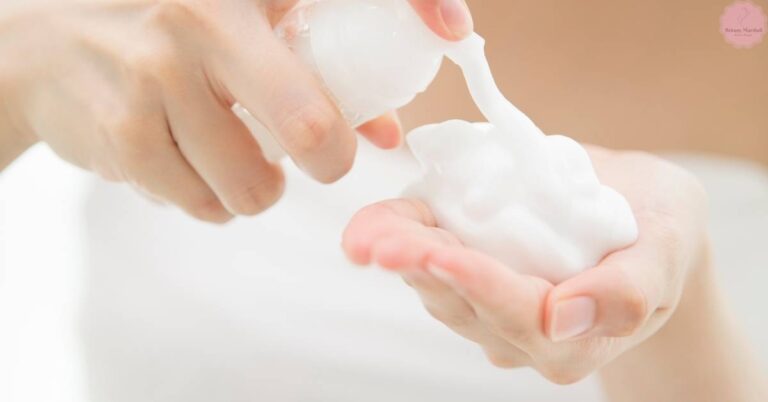 a pair of hands applying micellar water or eyelash wash to clean lash extensions gently