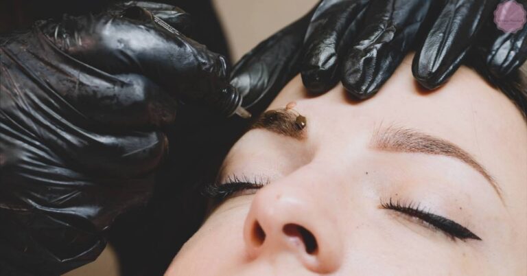 a technician performing microblading on a client’s thin eyebrows with precision using black gloves.