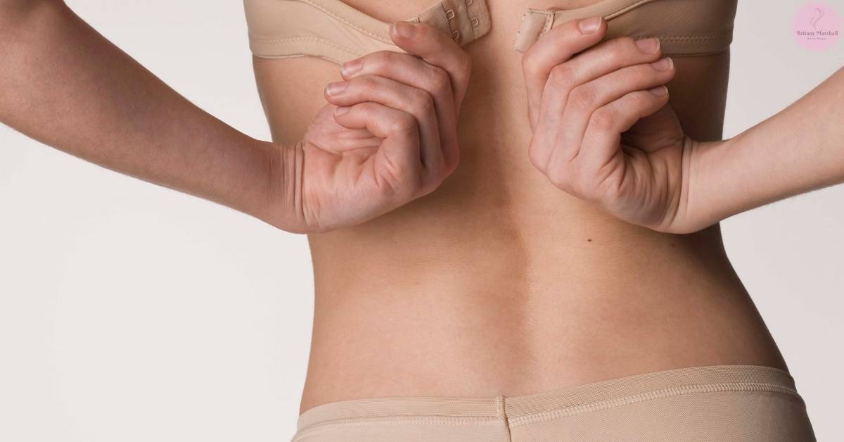 a person adjusting a minimizer bra straps, highlighting potential breast discomfort or fit issues.