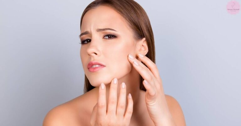 a person touching their shiny complexion near the ear, indicating concerns with oily skin.
