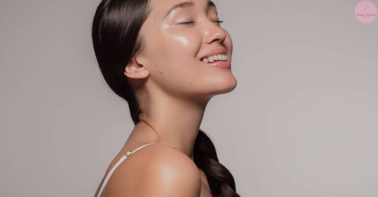 a woman with pale skin tone applying a light skincare product, smiling with eyes closed.