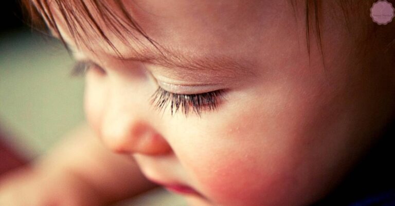 a close-up of a baby’s delicate eyelashes and partially closed eye, showcasing early eyelash development.
