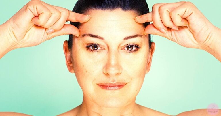 a person demonstrating how to check forehead skin tone differences, with hands lifting eyebrows to highlight potential uneven skin tone or discoloration.