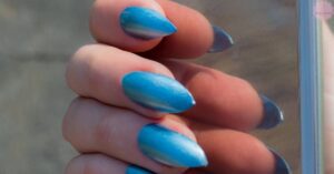 a close-up of acrylic coffin-shaped nails painted in a gradient light blue summer manicure.