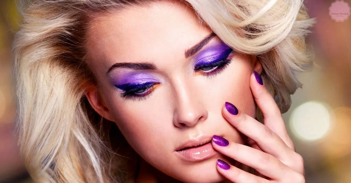 a person with pale skin gently touching their face, showcasing bold purple eyeshadow and matching deep purple nail polish.