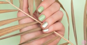 a hand holding woven natural fibers with a green nail design featuring coffin nails in dark forest green and speckled glitter accents