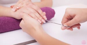 a professional nail technician trimming an almond-shaped nail with precision near the cuticle for elegant french tip inspiration.