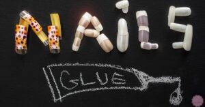 various types of nail glue capsules and pills arranged to spell "NAILS" with chalked text "GLUES" and a dripping glue icon below.