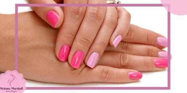 a hand showcasing a gradient nail design in light pink, mauve, and periwinkle shades on pale skin