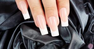 a close-up of neatly manicured hands showcasing clean V French tip nails on short, squared nails