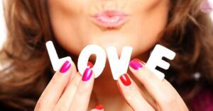 a person holding white block letters spelling "love" with brightly colored, romantic Valentine’s Day-inspired coffin-shaped nails.