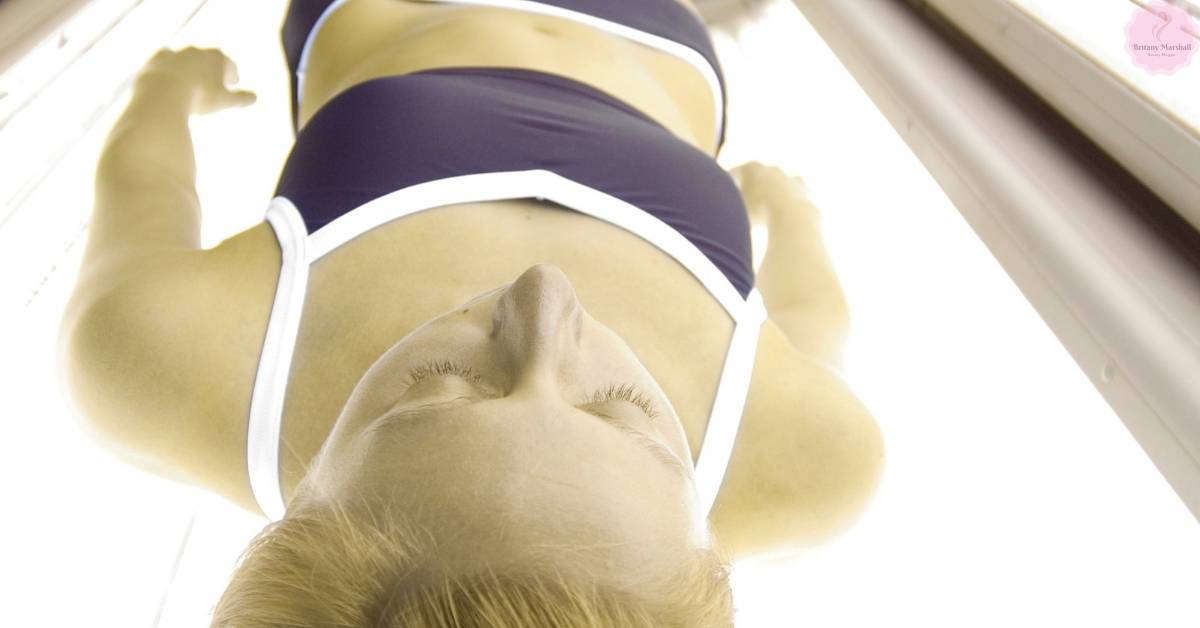 a person lying on a tanning bed in a salon getting a tan with arms raised