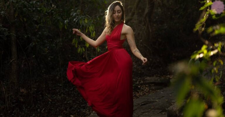 a woman in a flowing red halter dress posing gracefully outdoors, ideal for exploring nail colors that complement red attire.